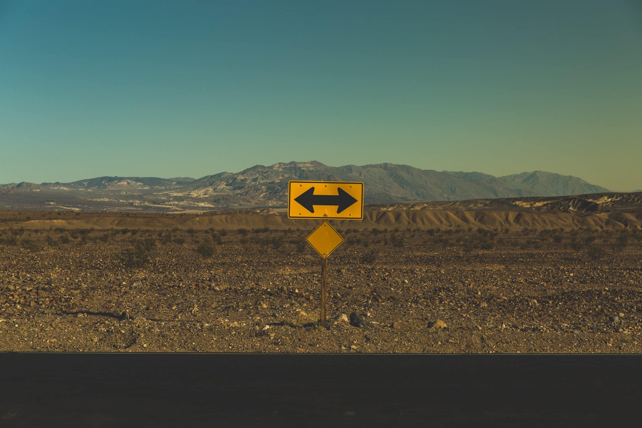 A photo of a desert with a traffic sign with arrows pointing in opposite directions representing bidirectional sandbox seeding