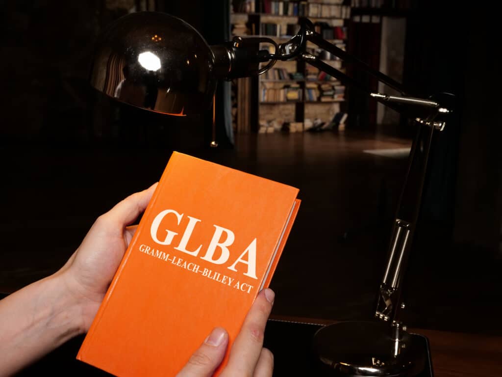 A man holding a book about GLBA compliance regulations.