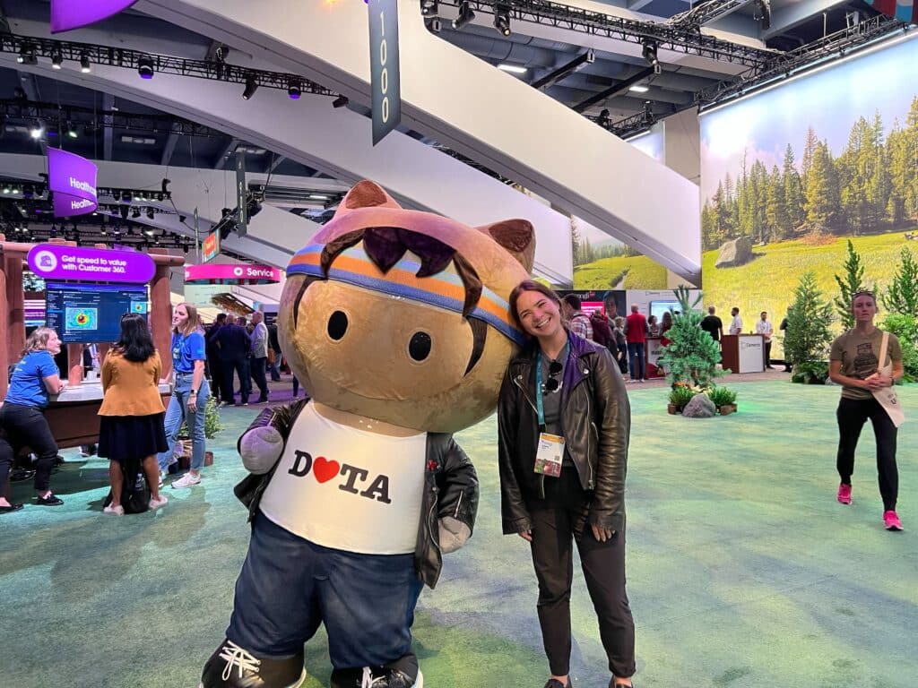 A Prodly employee posing with a Salesforce mascot at Dreamforce
